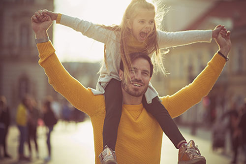 Father carrying daughter on shoulders outdoors